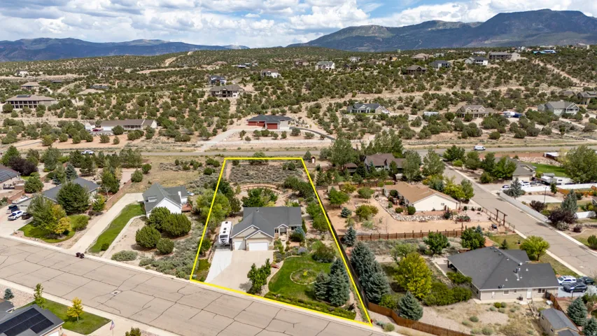 Single-story residence with an attached two-car garage, mature landscaping, and a paved driveway