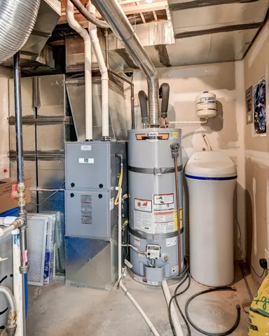 Mechanical room featuring a water heater, furnace, and water filtration system
