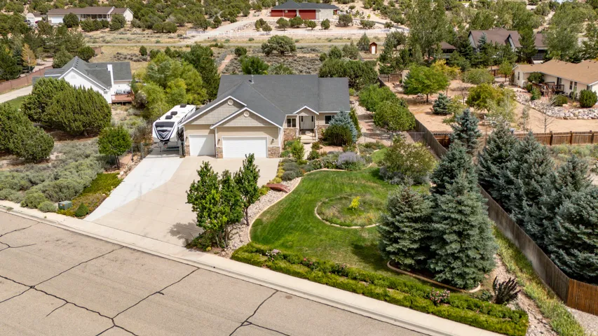 Expansive front yard with manicured lawn and mature evergreens, concrete driveway, attached two-car garage, and a blend of stone and siding exterior
