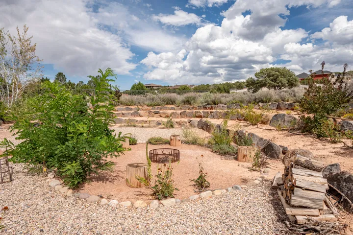 Terraced outdoor space with natural stone retaining walls, gravel pathways, a central fire pit, and mature landscaping
