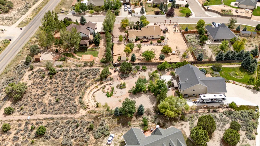 Expansive property with a tan facade and dark gray roof, featuring mature trees and a substantial paved driveway