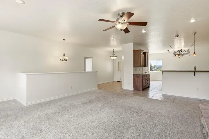 Neutral tone wall paint, recessed lighting, ceiling fan light fixture, tile flooring, and a built-in wood-finish cabinet