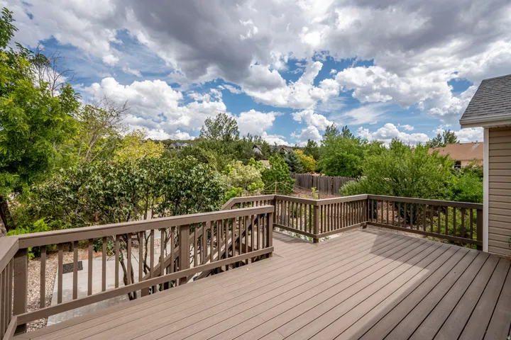 Expansive outdoor deck with wood-finish railing and siding, providing ample space for outdoor activities