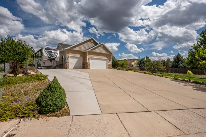 Exterior featuring a two-car garage, stone accents, and a wide concrete driveway