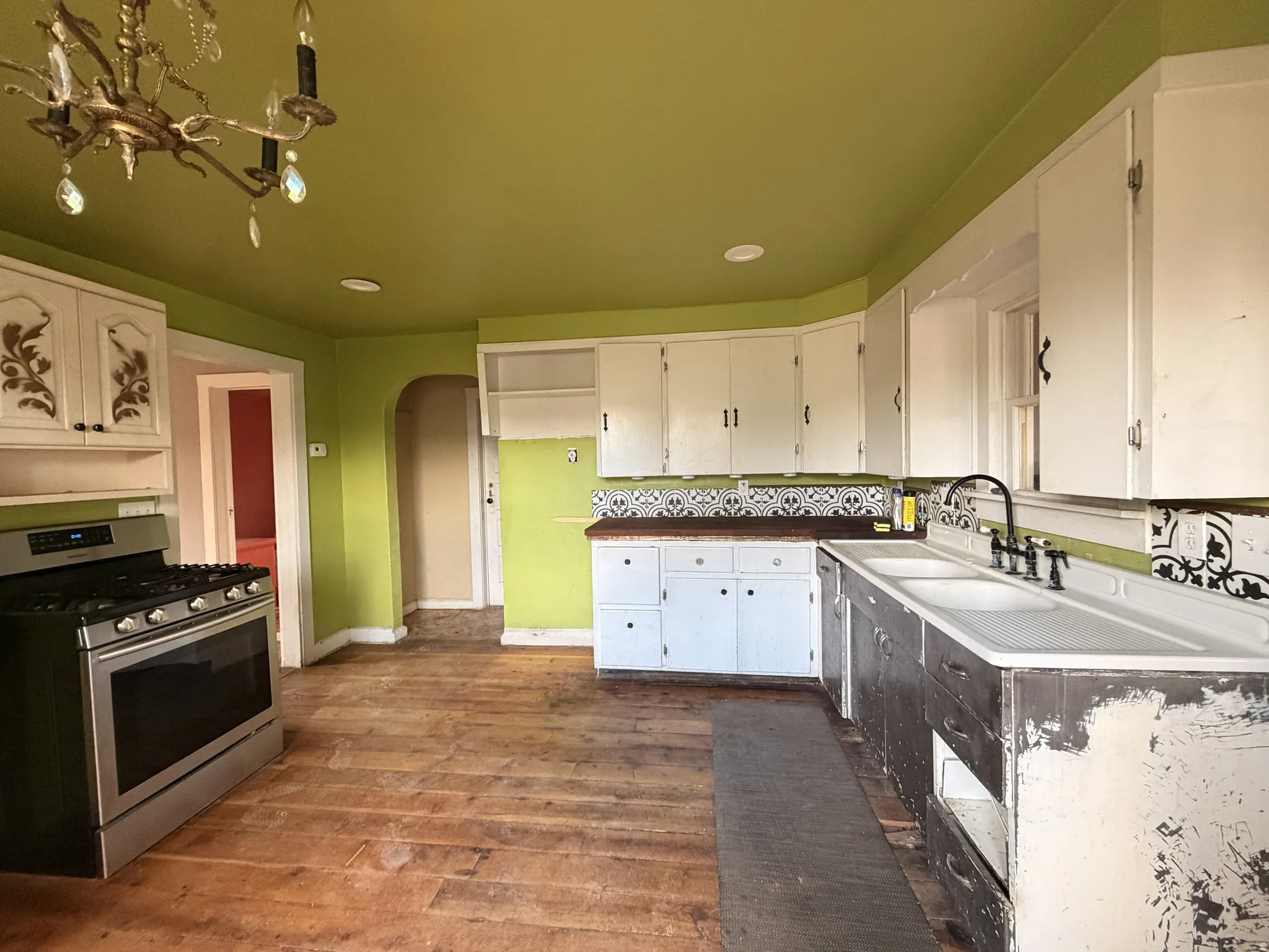 Kitchen featuring a gas range, white cabinetry, decorative backsplash, and chandelier lighting