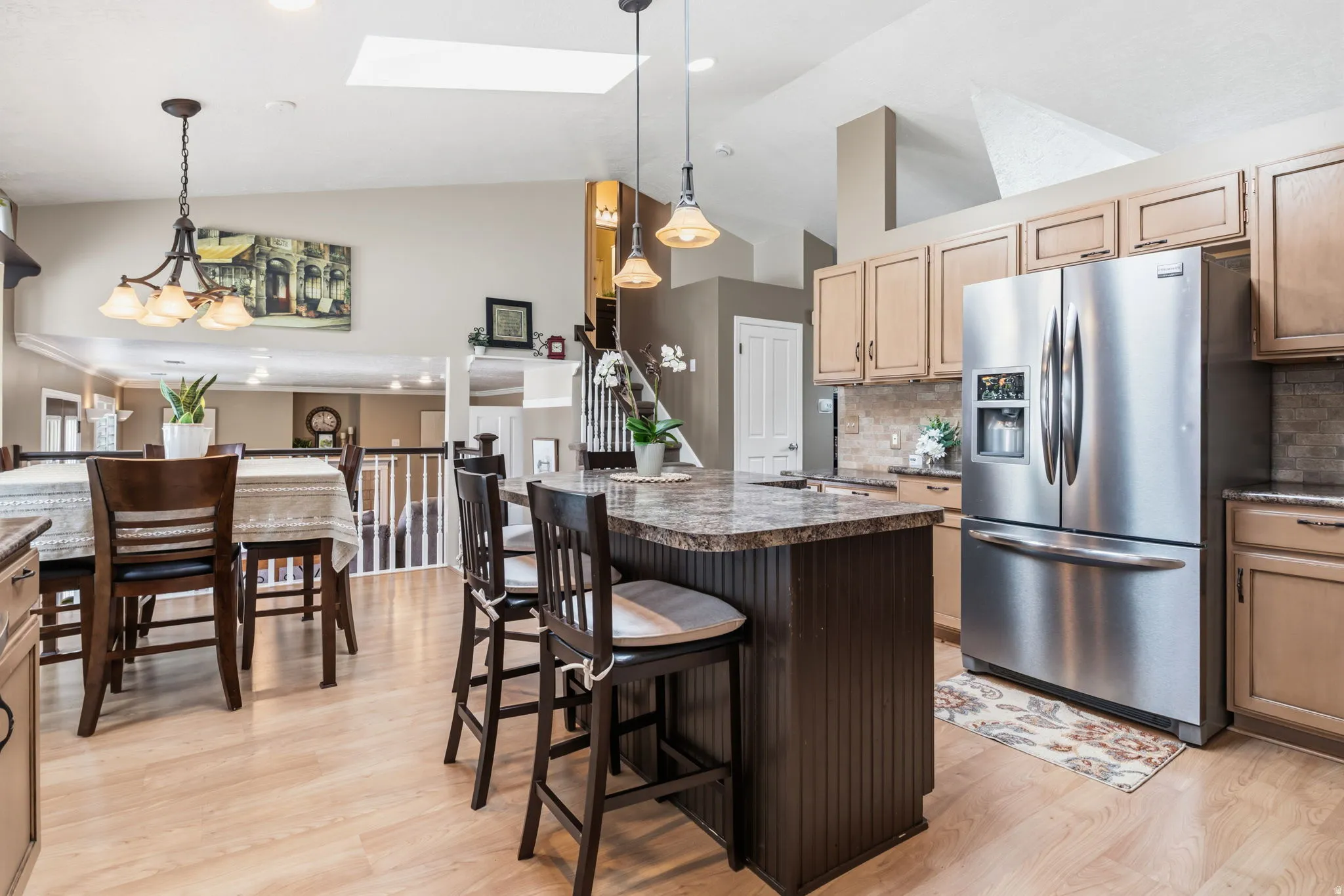 Kitchen featuring a skylight, wood-finish flooring, a central island with a stone-finish countertop, and stainless steel appliances