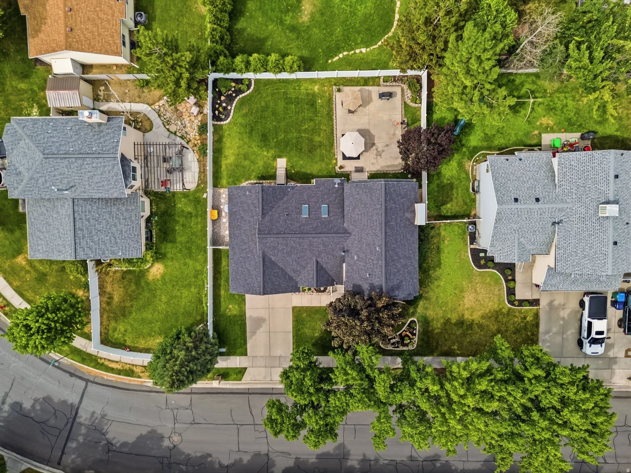 Expansive rear yard featuring a concrete patio, manicured lawn, and privacy fencing