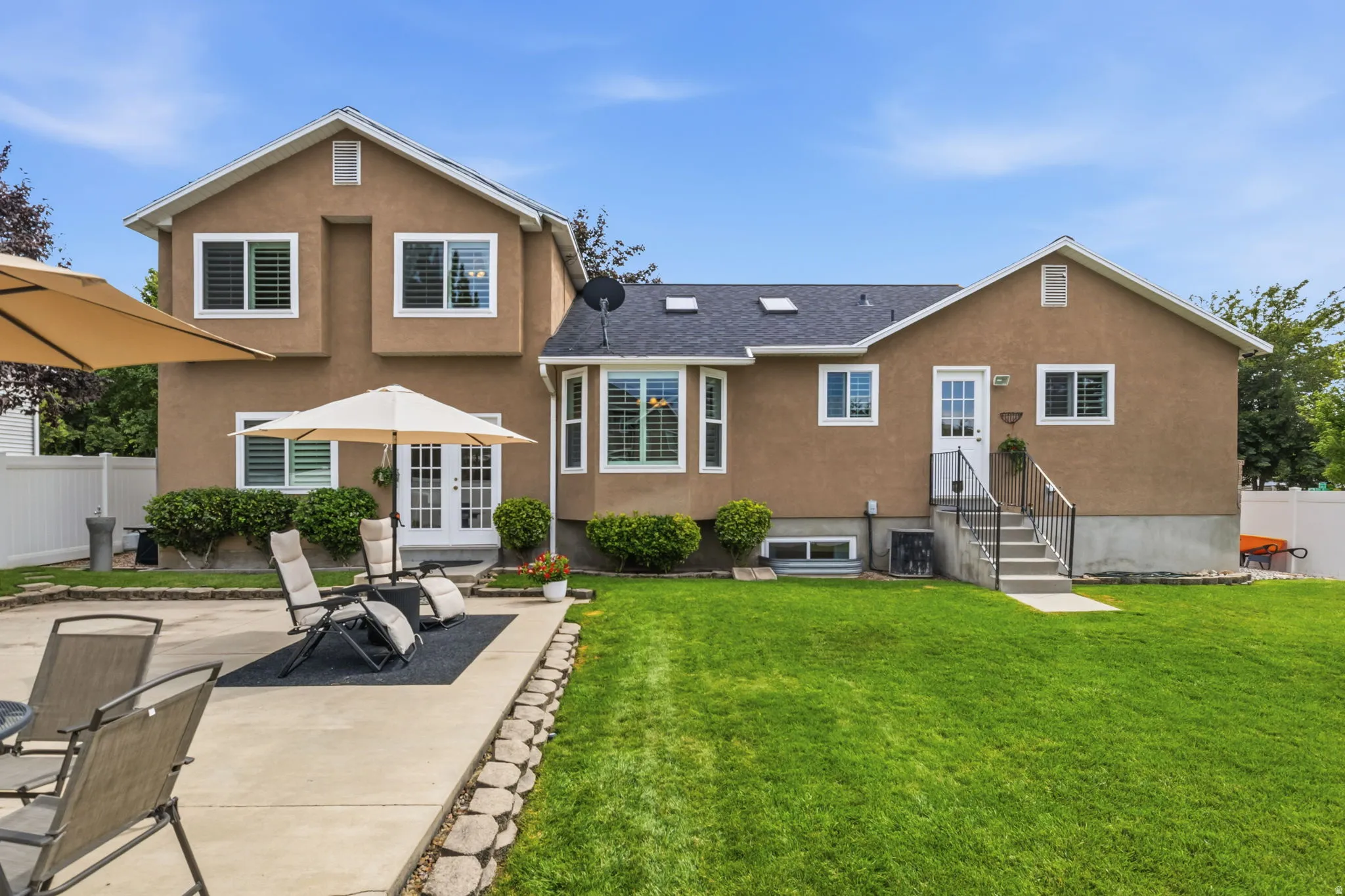 Expansive backyard featuring a lush lawn, concrete patio, and mature shrubbery