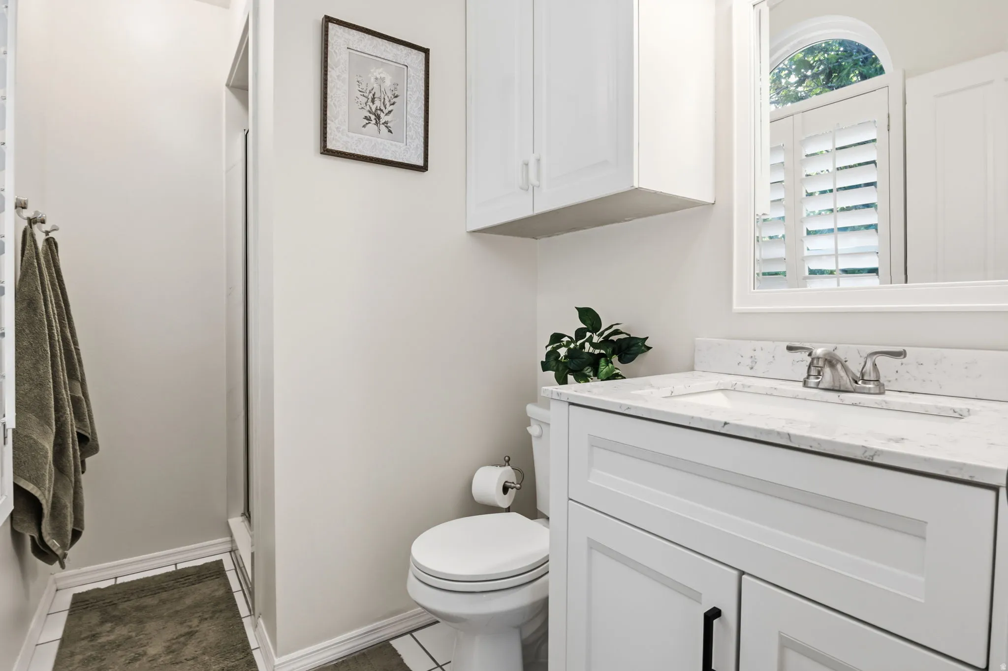 White vanity with a light-toned countertop, under-mount sink, and dual-handle faucet
