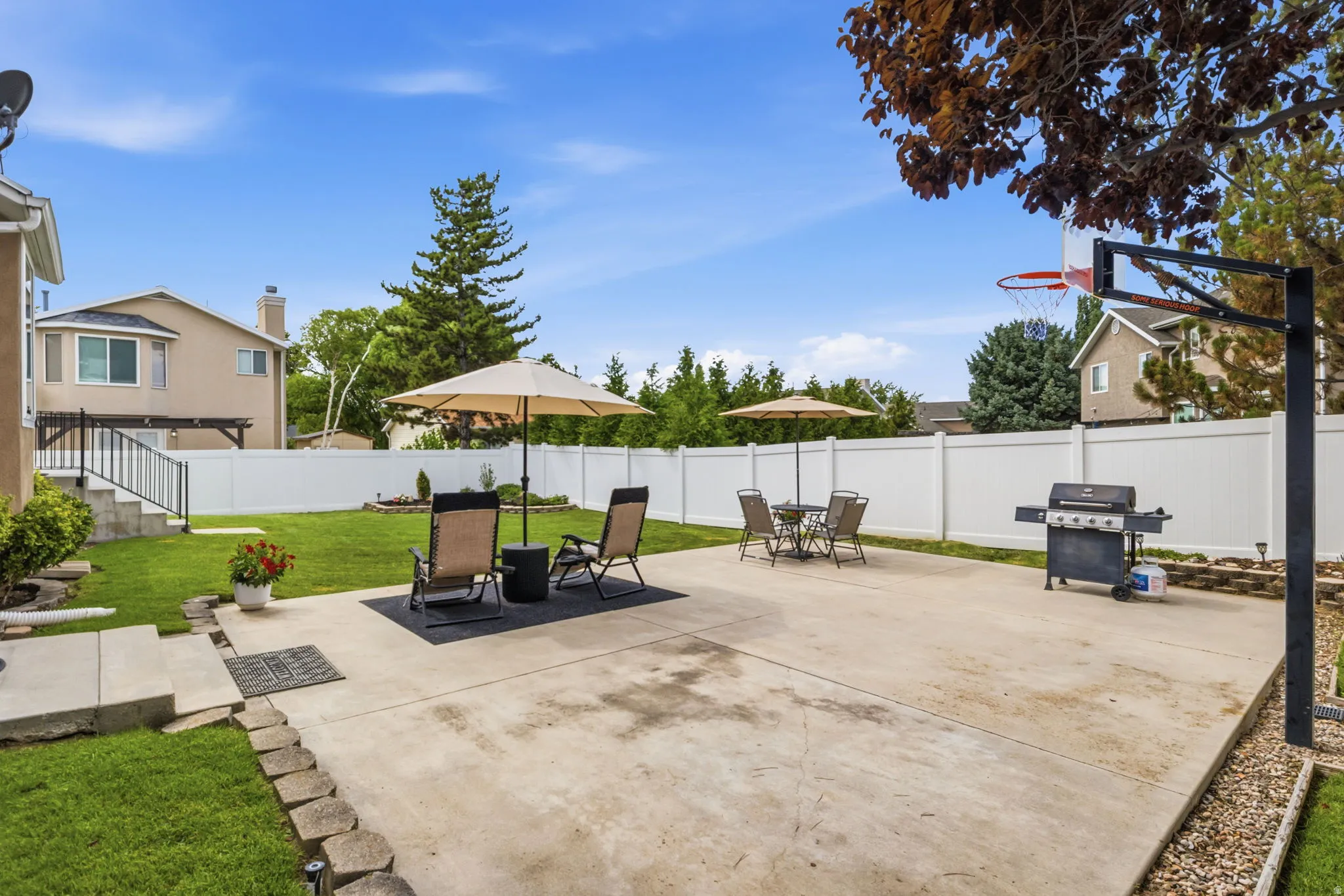 Expansive backyard featuring a large concrete patio, manicured lawn, and a full privacy fence
