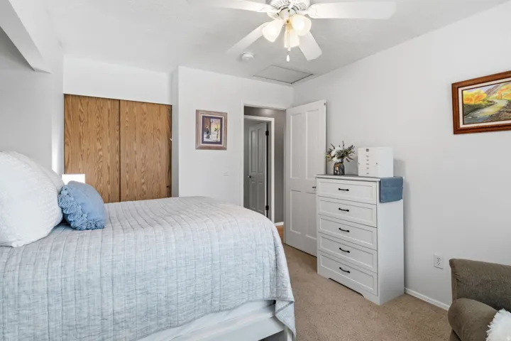 Recessed lighting, wood-finish sliding closet doors, white paneled door, ceiling fan with light fixture, and neutral carpeting