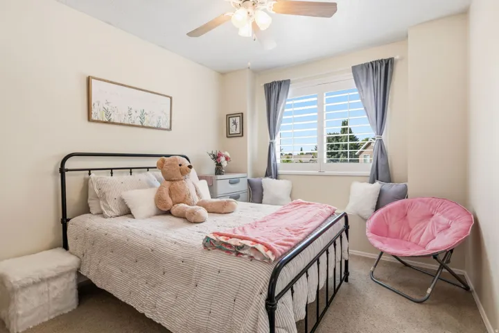 Window with plantation shutters, ceiling fan with integrated lighting, wall-to-wall carpeting