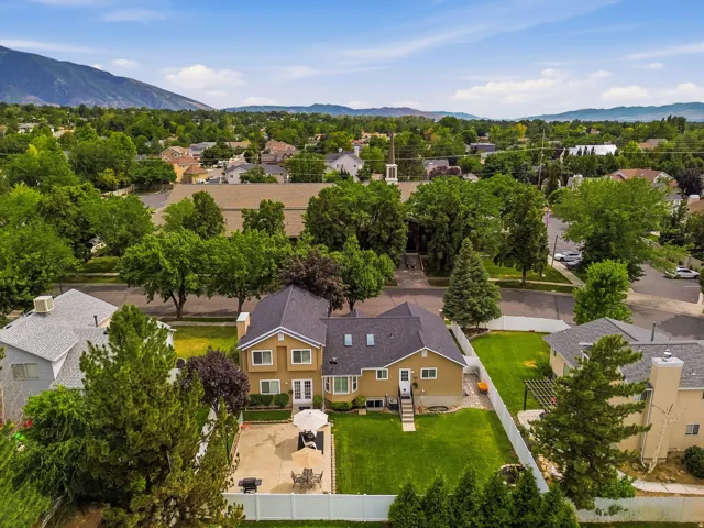 Expansive property featuring a large patio, manicured lawn, and mature trees