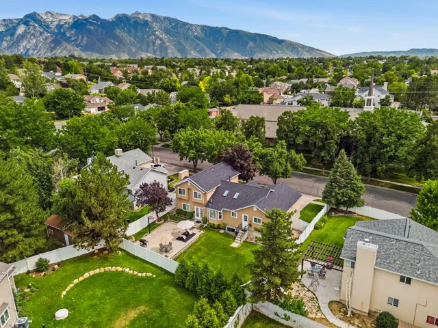 Expansive backyard featuring a large green lawn, paved patio, and white privacy fencing