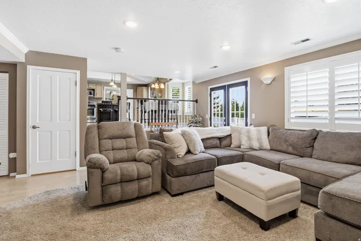 Recessed lighting, wood-finish flooring, white four-panel door, white plantation shutters, and French doors