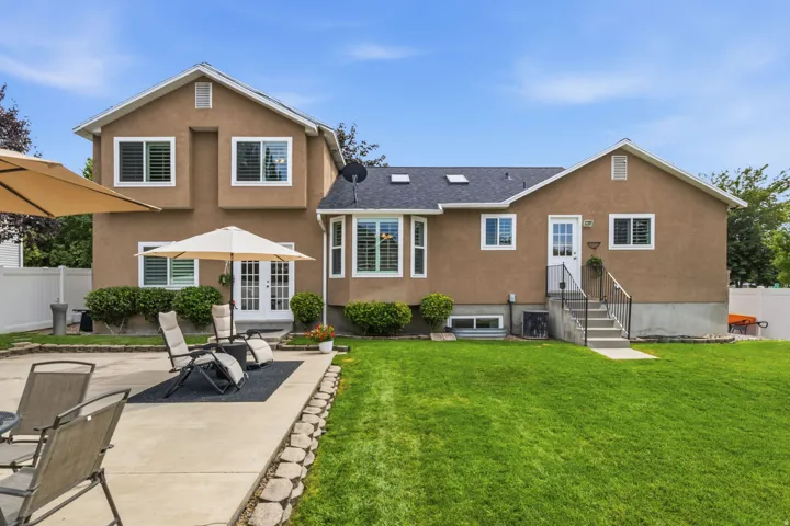 Expansive backyard featuring a lush lawn, concrete patio, and mature shrubbery