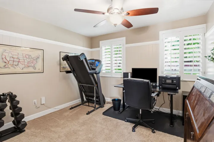 Beige carpeting, white wainscoting, and white window shutters