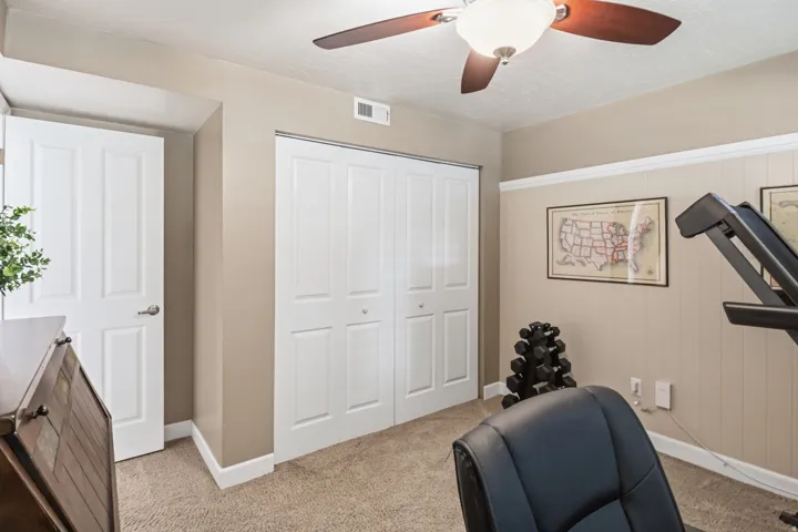 Carpeted flooring, bi-fold closet doors, ceiling fan with integrated lighting, and neutral wall tones