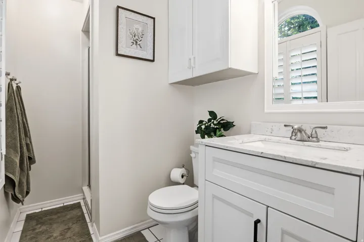 White vanity with a light-toned countertop, under-mount sink, and dual-handle faucet