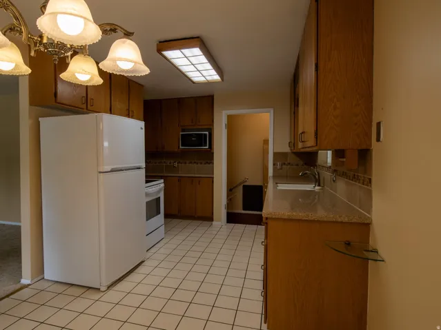Kitchen featuring wood-finish cabinetry, tile flooring, and a built-in microwave