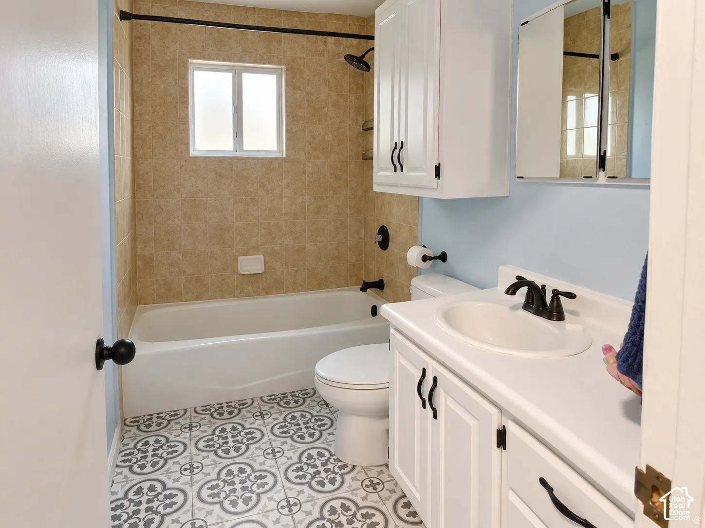 Bathroom featuring patterned floor tile, vanity with white cabinetry, integrated sink, and matte black fixtures
