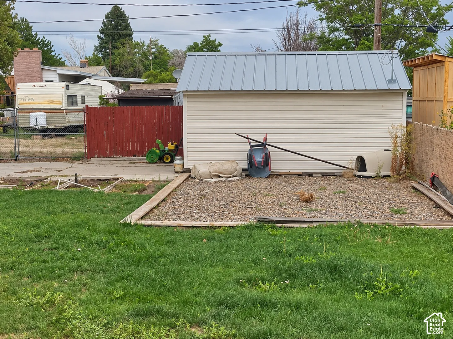 Detached structure with horizontal siding and a metal roof, complemented by a gravel ground cover area bordered by timber edging