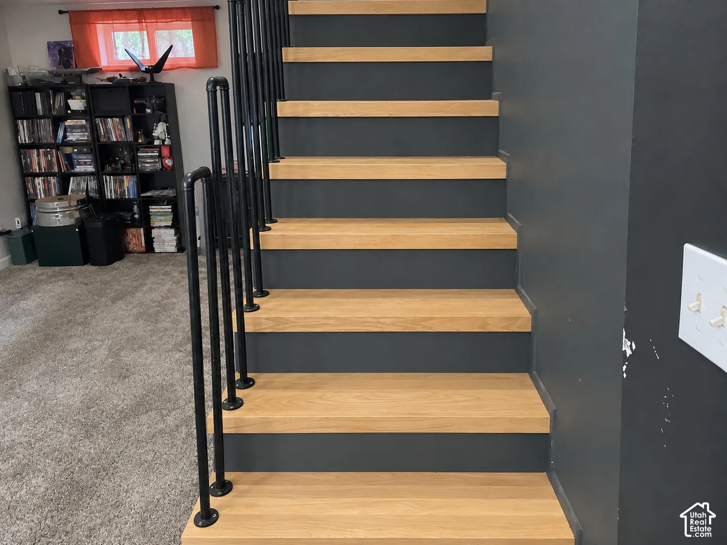 Staircase featuring natural wood-finish treads, solid charcoal risers, and industrial-style matte black metal railing
