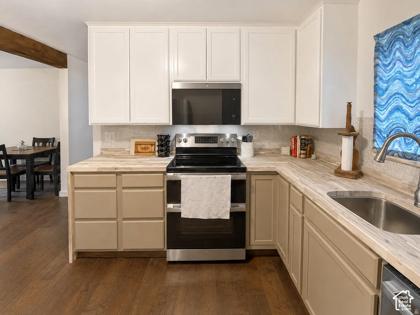 Kitchen featuring two-tone cabinetry, wood-finish countertops, stainless steel appliances, and wood-finish flooring