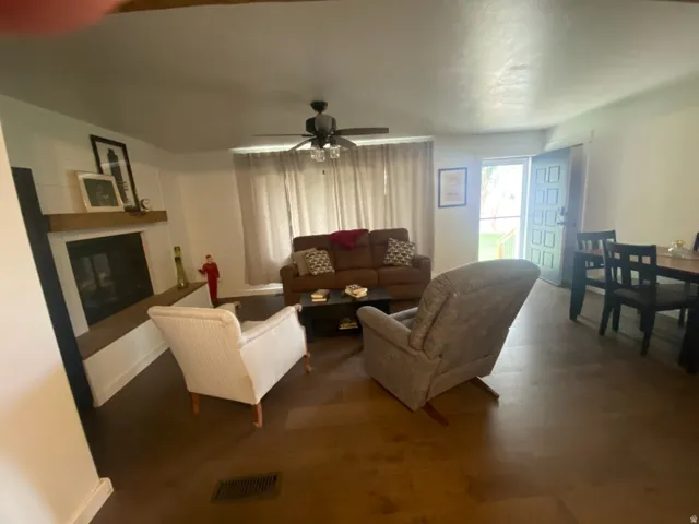 Wood-finish flooring, built-in fireplace with mantel, ceiling fan, and front door with glass paneling