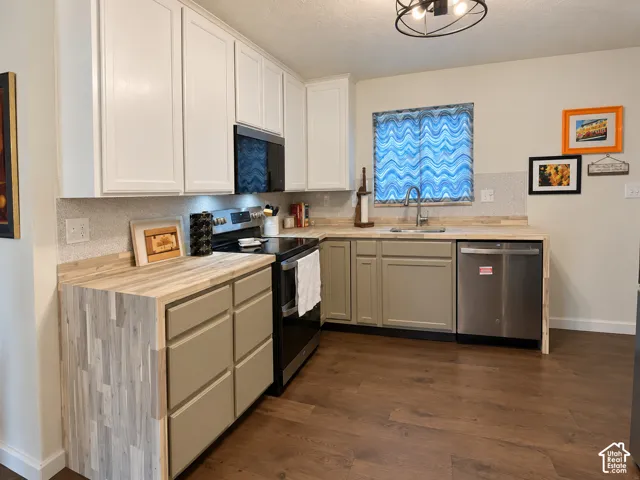 Kitchen featuring dual-tone cabinetry, butcher block countertops, wood-finish flooring, stainless steel dishwasher, and a built-in microwave