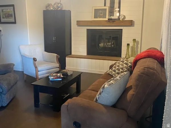 Fireplace with wood mantle, wood-finish flooring, ceiling fan with integrated lighting, shiplap wall detail