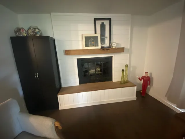 Fireplace featuring a substantial wood mantel, shiplap wall detail, and a built-in hearth bench