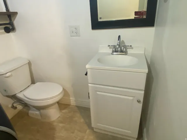 White vanity with an integrated sink, chrome faucet, and a wall-mounted mirror