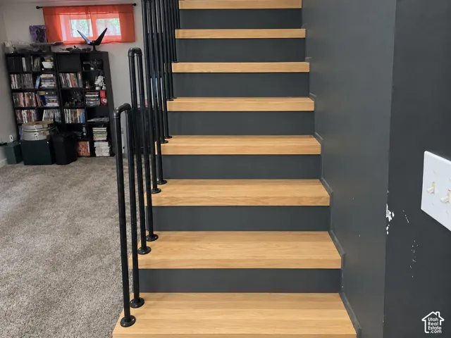 Staircase featuring natural wood-finish treads, solid charcoal risers, and industrial-style matte black metal railing
