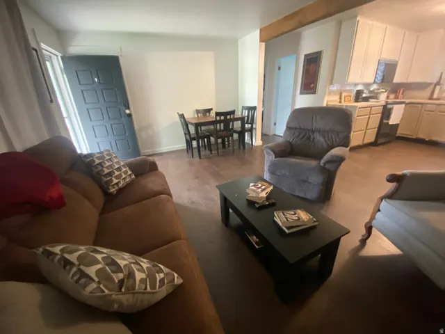 Wood-finish flooring throughout, framed entry door, kitchen with light cabinetry and solid countertops, dining area with dark wood-finish table