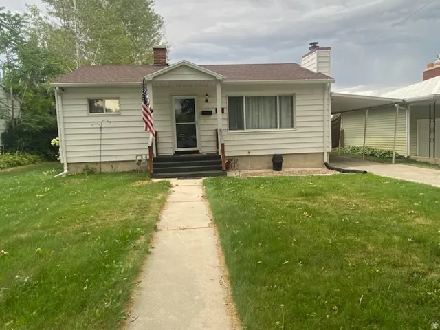 White siding exterior with a brown shingle roof, a covered entry, and a concrete walkway
