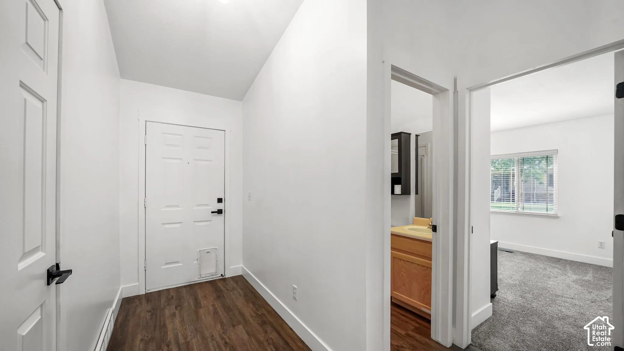 Entryway featuring wood-finish flooring, white paneled doors, and white walls