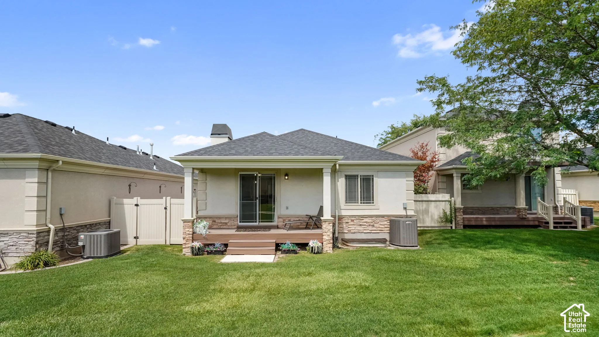 Expansive lawn with a covered patio featuring a wood-finish deck and sliding glass door access