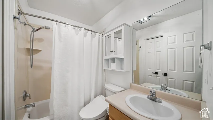 Bathroom featuring a built-in tub and shower combination, vanity with an integrated sink, wall-mounted mirror, and overhead storage cabinetry