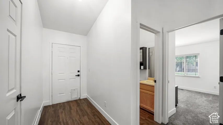 Entryway featuring wood-finish flooring, white paneled doors, and white walls