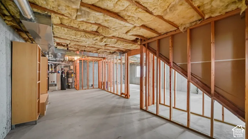 Unfinished basement with exposed ceiling insulation, wood framing, concrete flooring, and visible utility infrastructure
