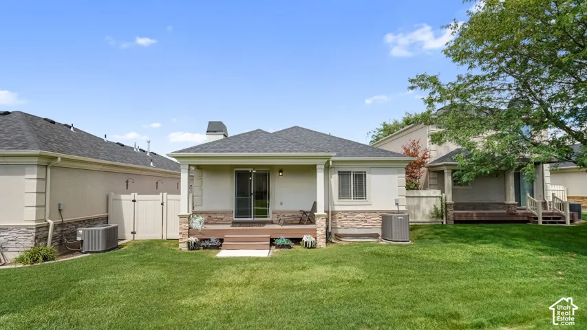 Expansive lawn with a covered patio featuring a wood-finish deck and sliding glass door access