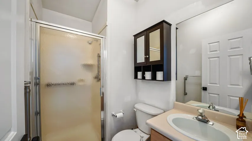 Enclosed shower stall with a frosted glass door, single vanity with an oval sink, wall-mounted mirror, and a dark wood-finish medicine cabinet