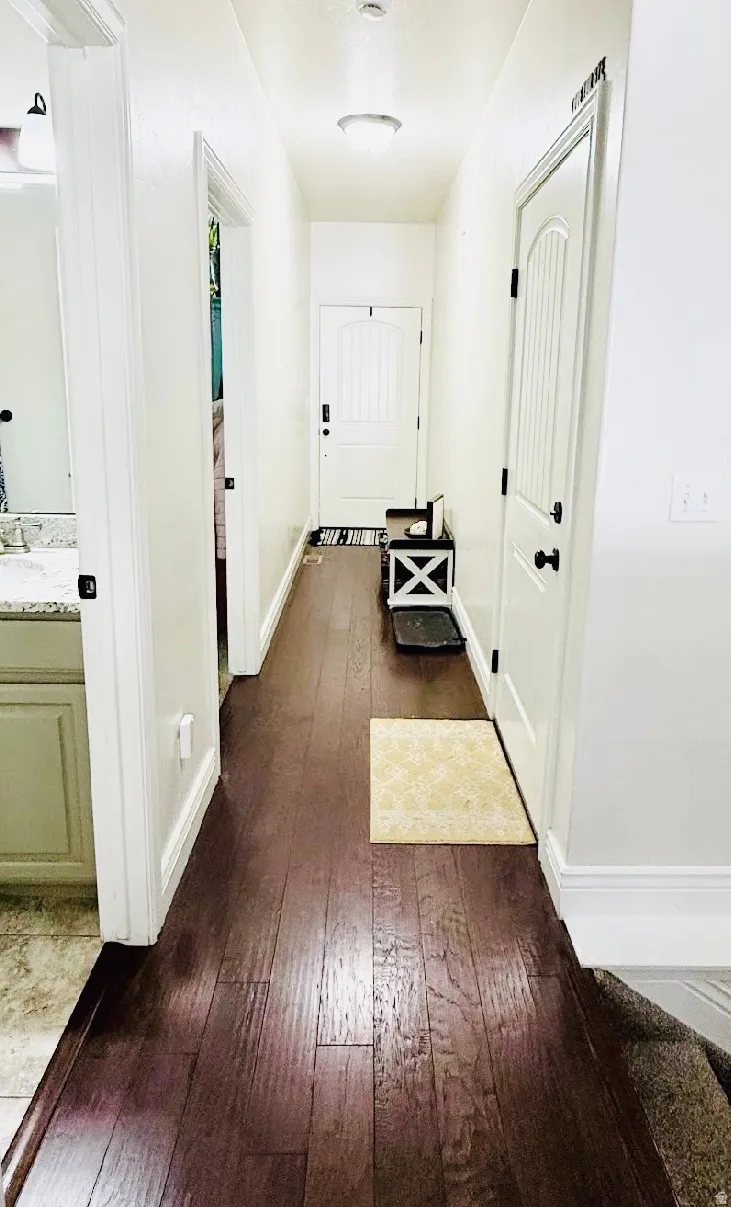 Wood-finish flooring throughout, white interior doors with dark hardware, and a bright overhead light fixture