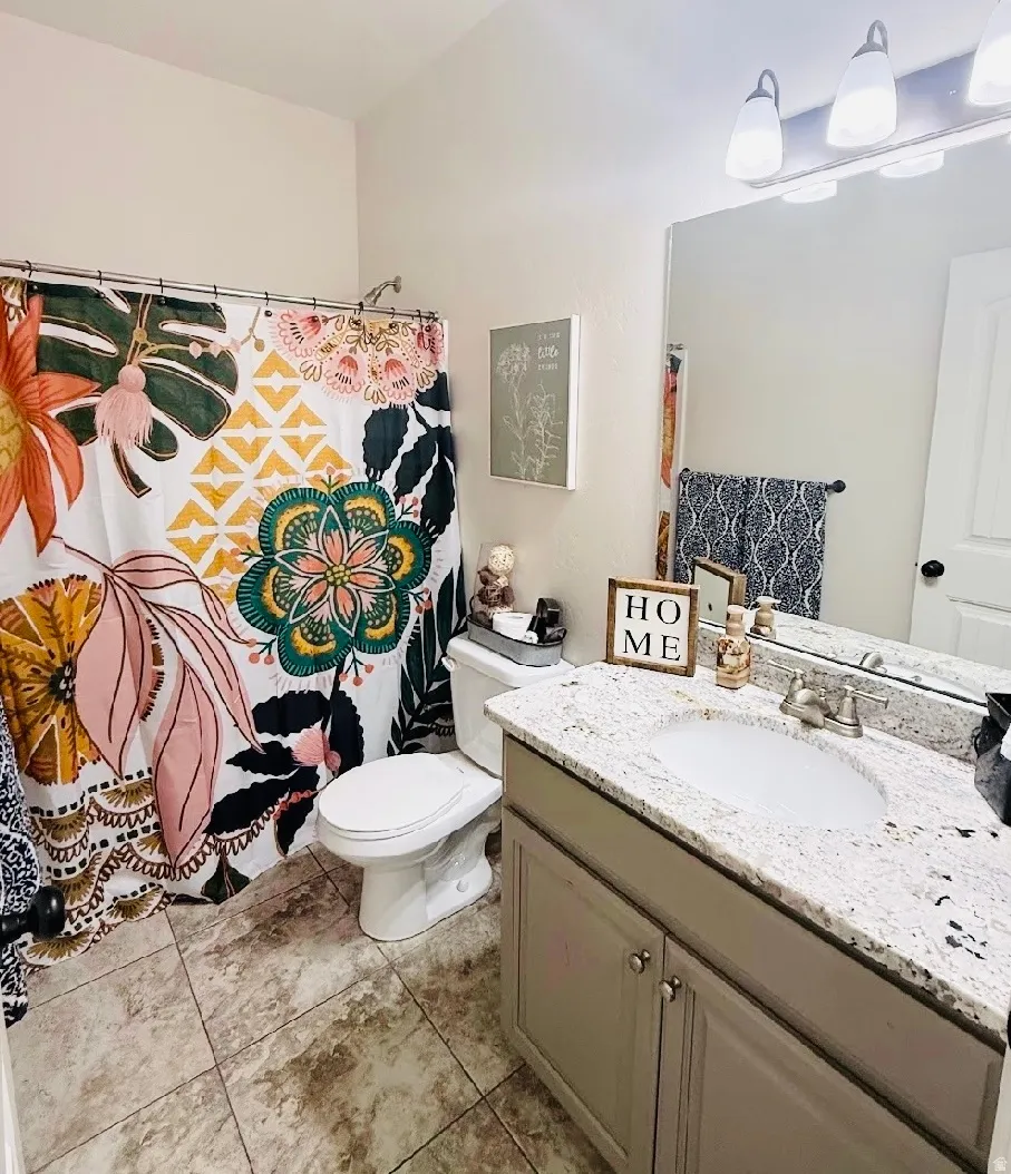 Bathroom with a shower, tile flooring, a single vanity with a solid surface countertop, and an integrated sink