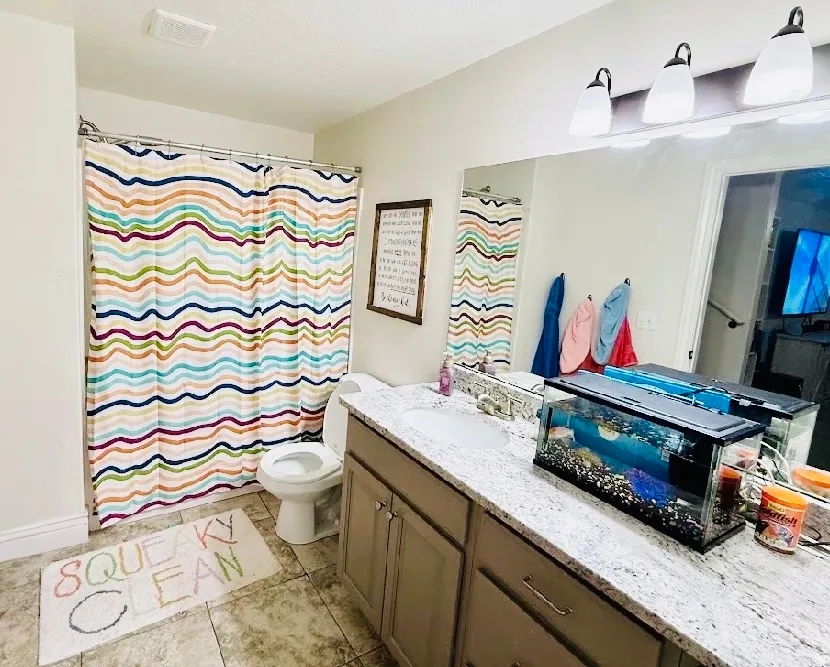 Bathroom featuring a single vanity with a white countertop, an undermount sink, and a framed mirror