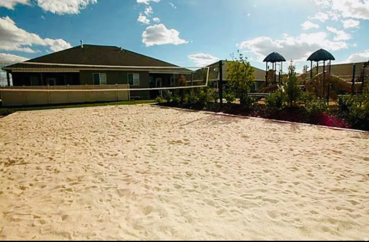 Outdoor sand court with net, adjacent to a structured play area
