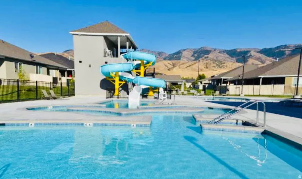 Resort-style aquatic amenity featuring a large swimming pool, integrated splash pad, and a multiple-slide structure