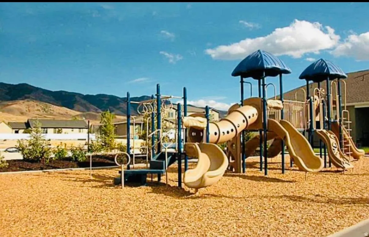 Outdoor play structure with multiple slides and climbing elements, set on a wood chip surface
