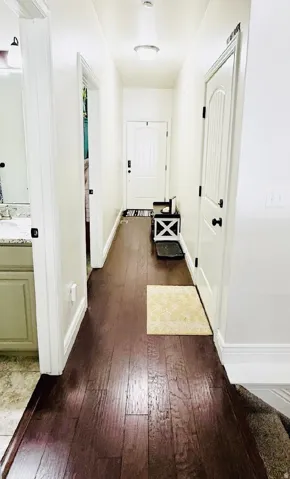 Wood-finish flooring throughout, white interior doors with dark hardware, and a bright overhead light fixture